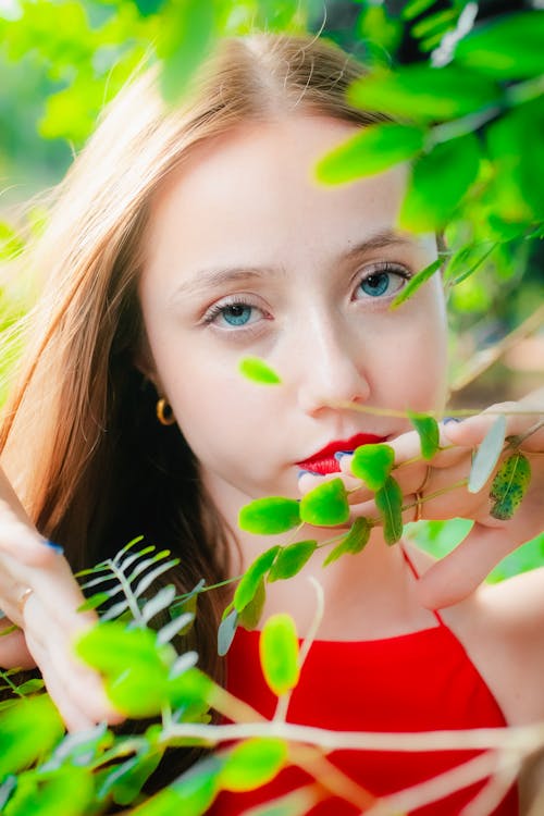 A girl with red lipstick and green leaves
