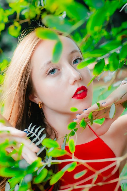 A woman in red dress with red lipstick and green leaves