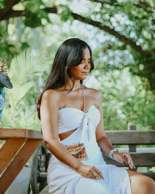 A woman in a white dress sitting on a bench