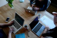 木桌上放着笔记本电脑、咖啡和文件，这是现代工作区的俯视图