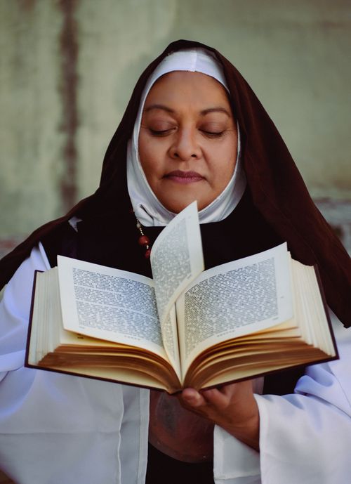 Free A serene nun reading a religious book in an indoor setting, embodying peace and devotion. Stock Photo