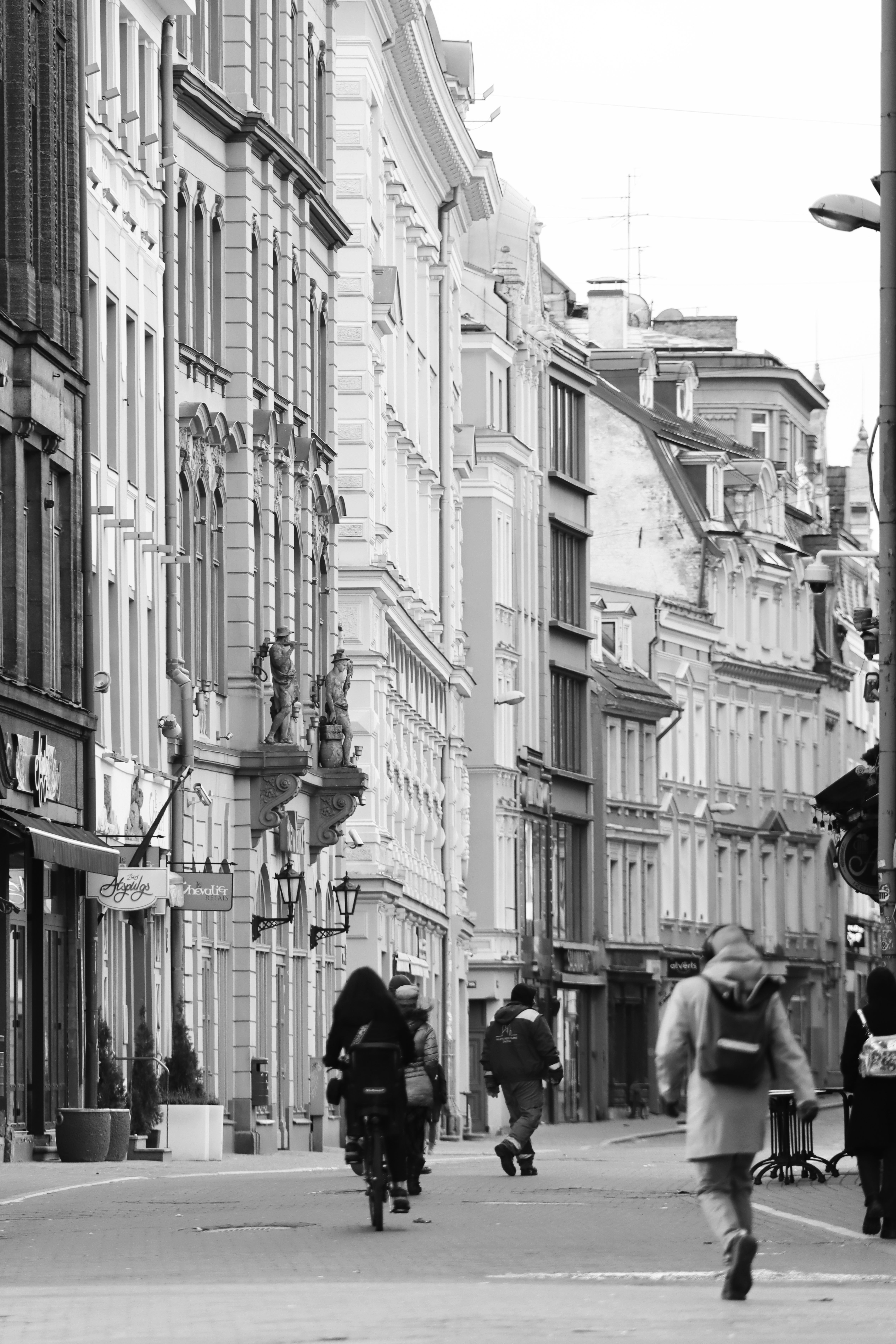 Black and white street scene in Old Riga, featuring historic architecture and pedestrians.