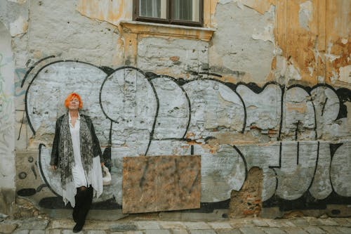 Woman with Orange Hair Standing by Cracked Wall with Tags