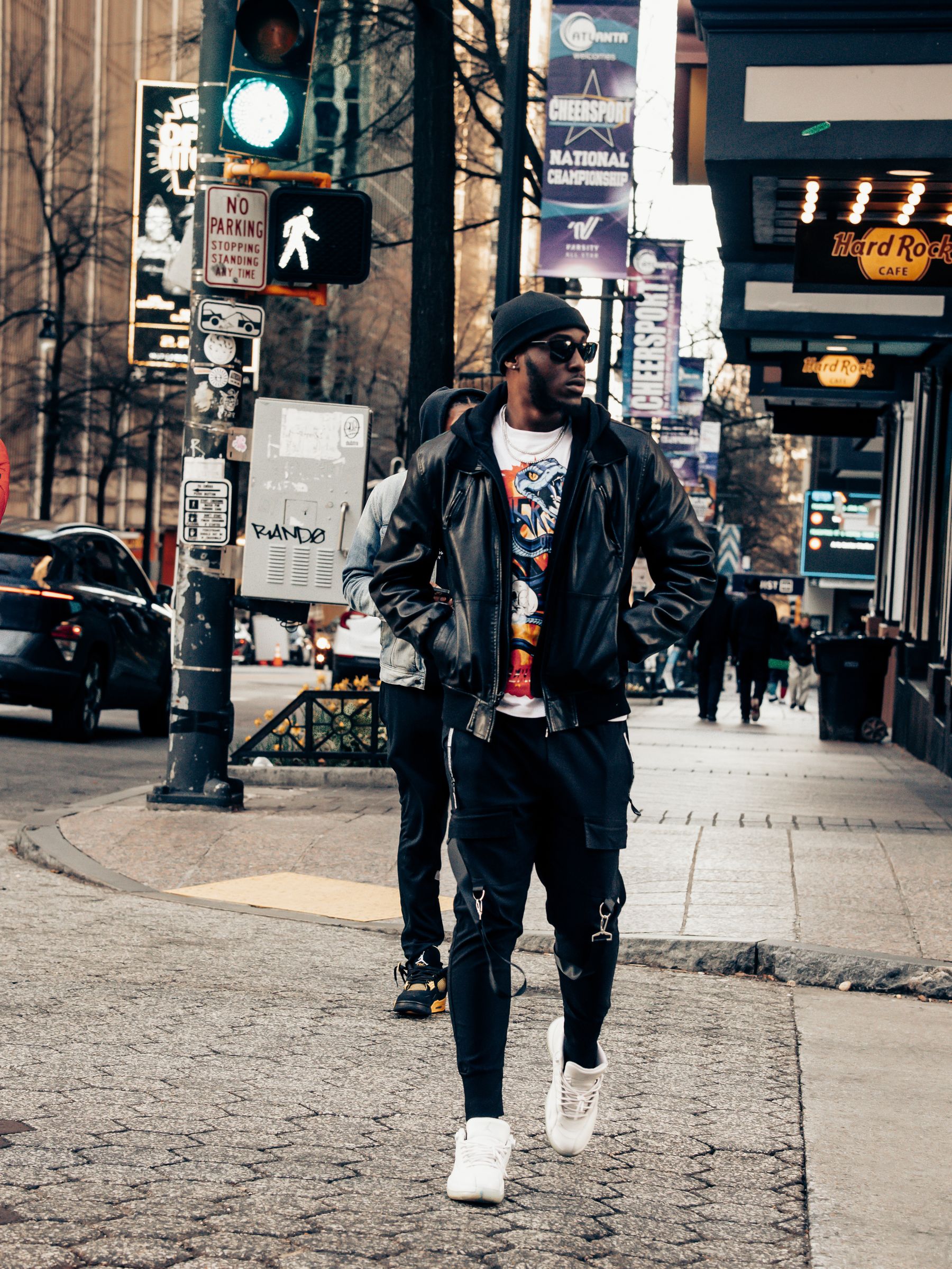 Black fashion model in premium streetwear walking through a city street