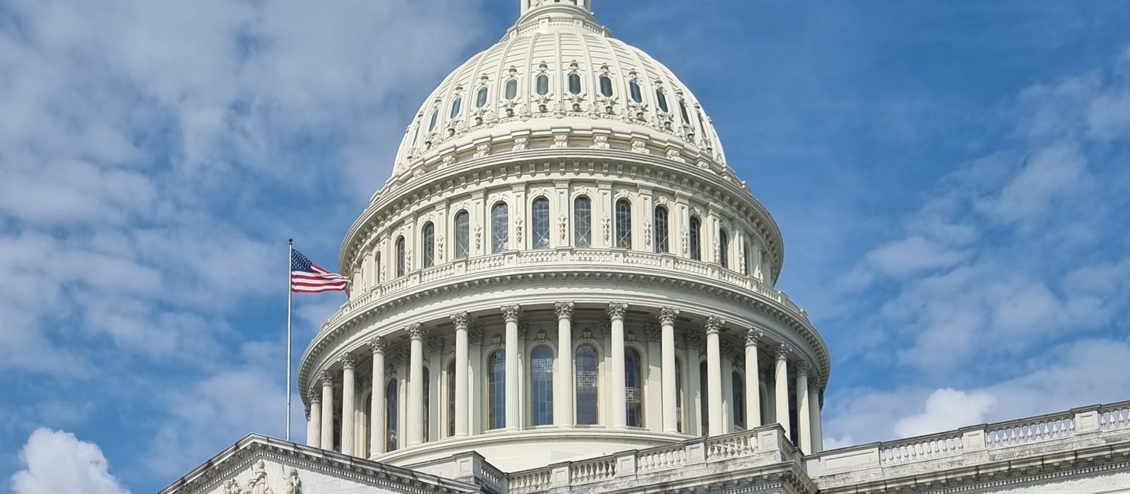 A striking view of the US Capitol dome with flag and blue sky in Washington, DC. — flights from Orlando to Washington