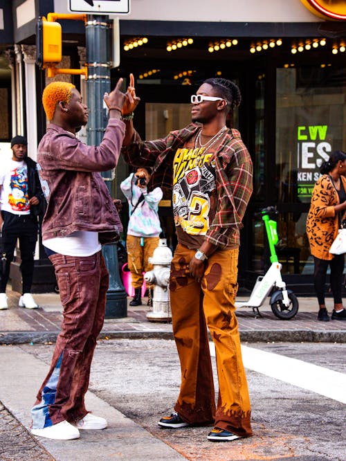 Two men are standing on the street and one is giving the other a high five