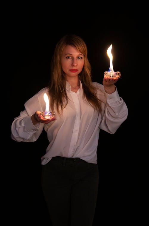 A woman holding two lit candles in her hands