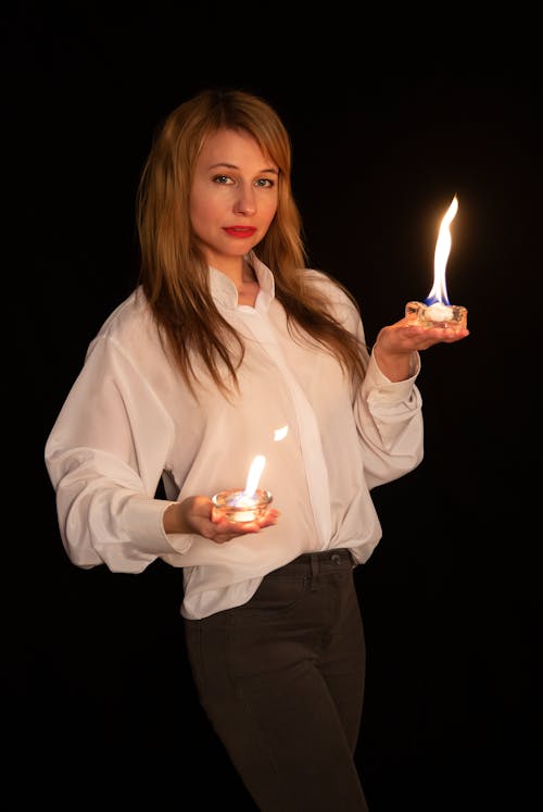 A woman holding two lit candles in her hands