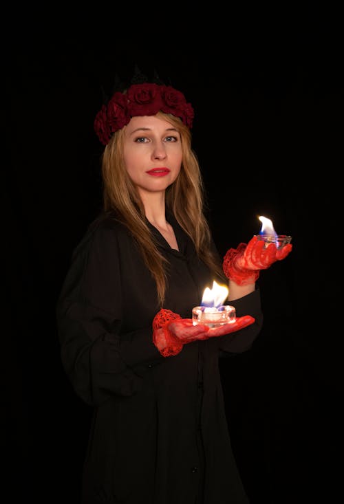 A woman in red gloves holding two candles