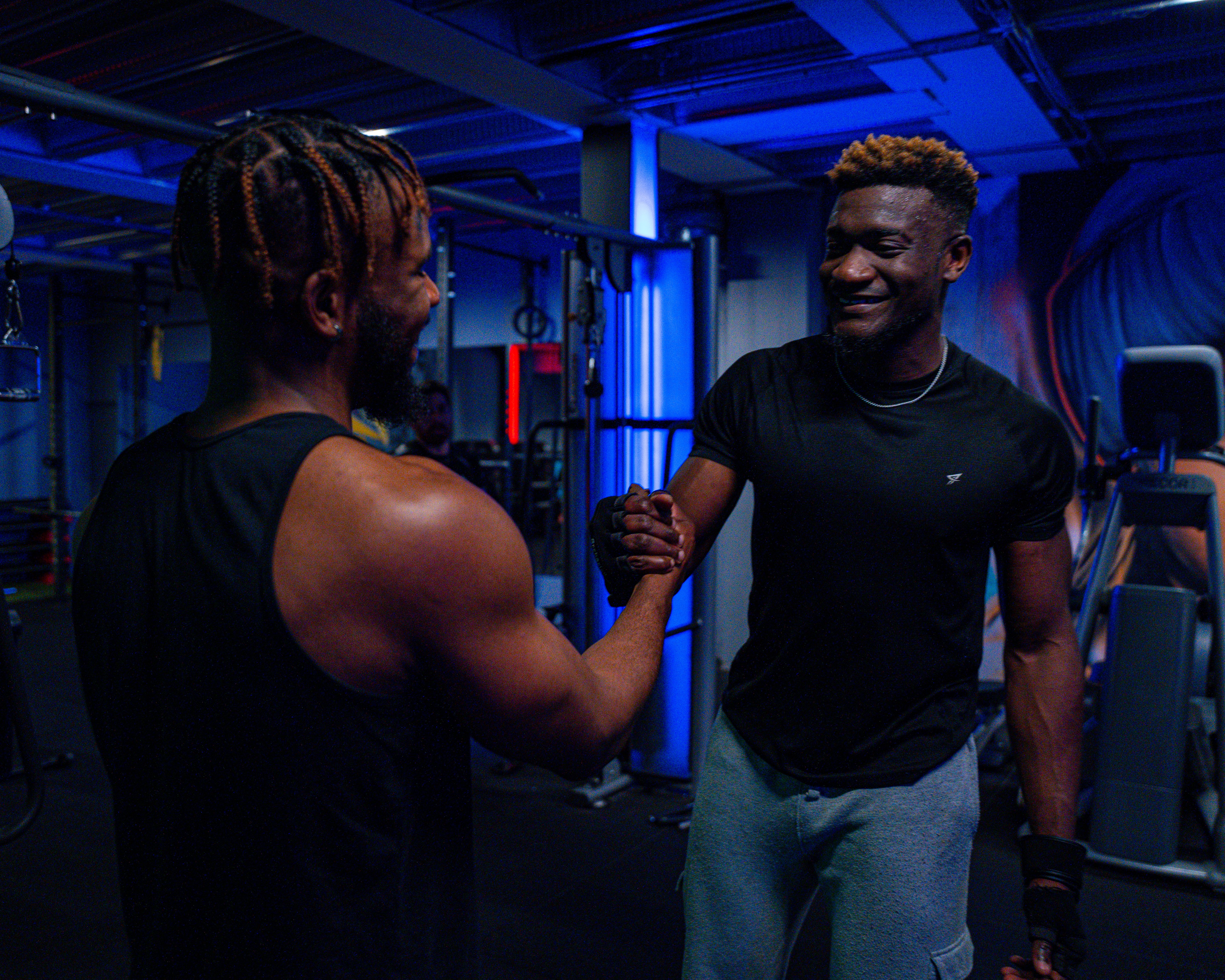 Two men in sportswear shaking hands in a modern gym, promoting friendship and teamwork.