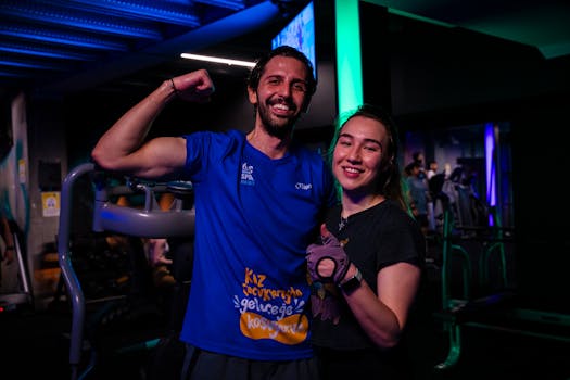 Happy couple in sportswear posing confidently at a gym, showing fitness enthusiasm.