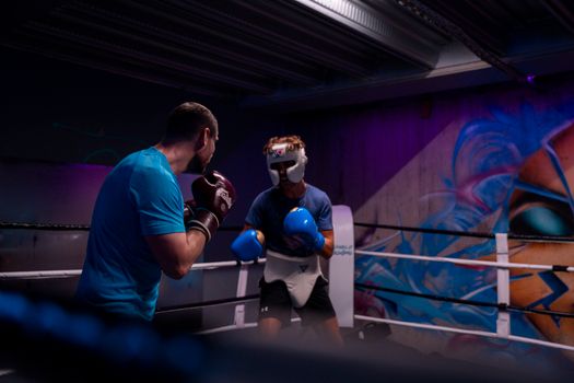 Two male boxers engaged in training in an indoor boxing ring with colorful graffiti.