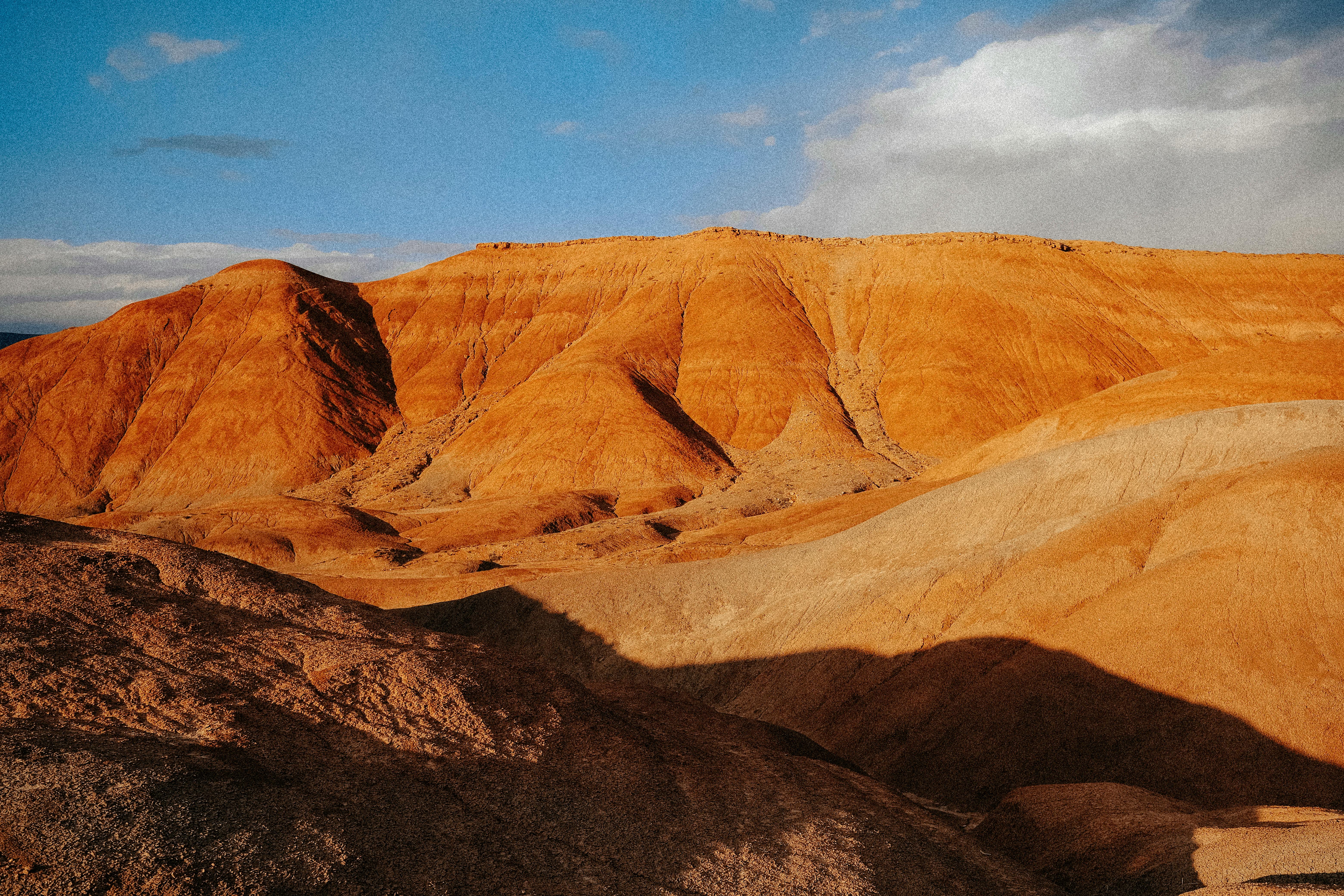 Captivating barren desert landscape with orange hills and a vivid blue sky.