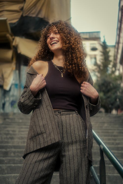 Smiling Woman with Curly Hair Standing in Suit