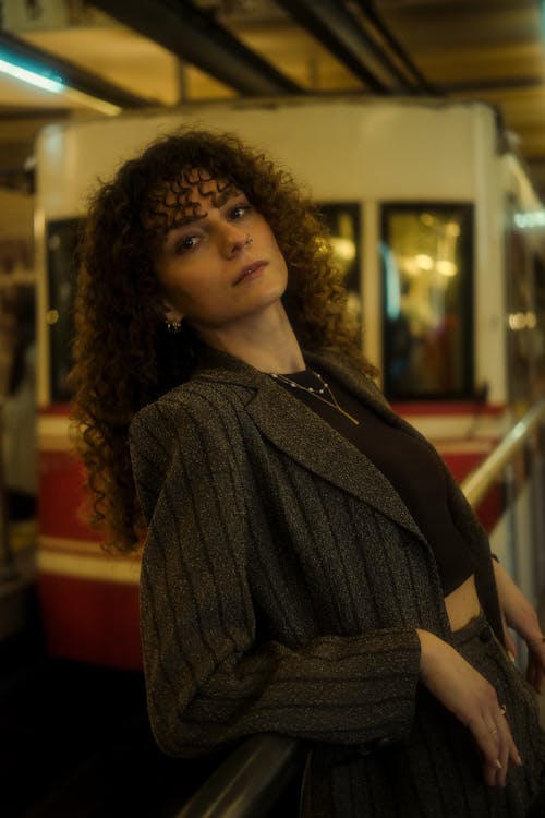 A woman with curly hair posing in front of a train