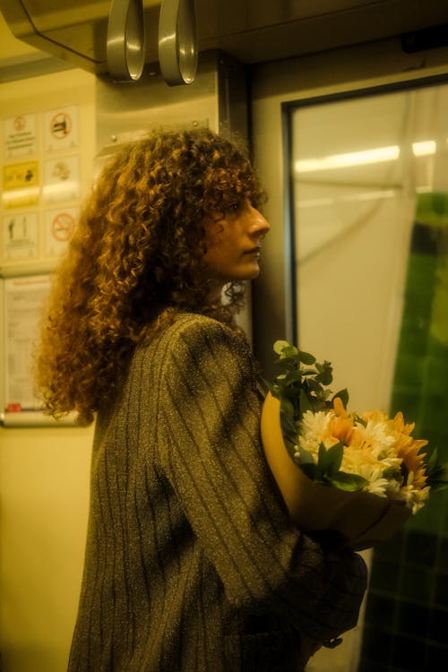 Woman with Curly Hair Standing with Flowers Bouquet on Metro