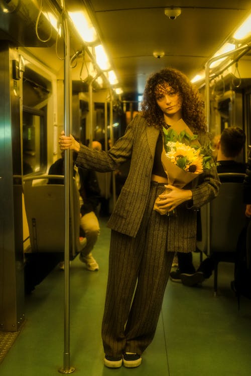 Woman in Suit Standing with Sunflowers Bouquet on Metro Train