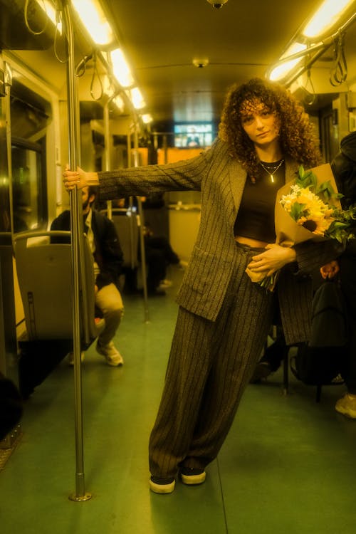 A woman in a suit holding flowers on a train