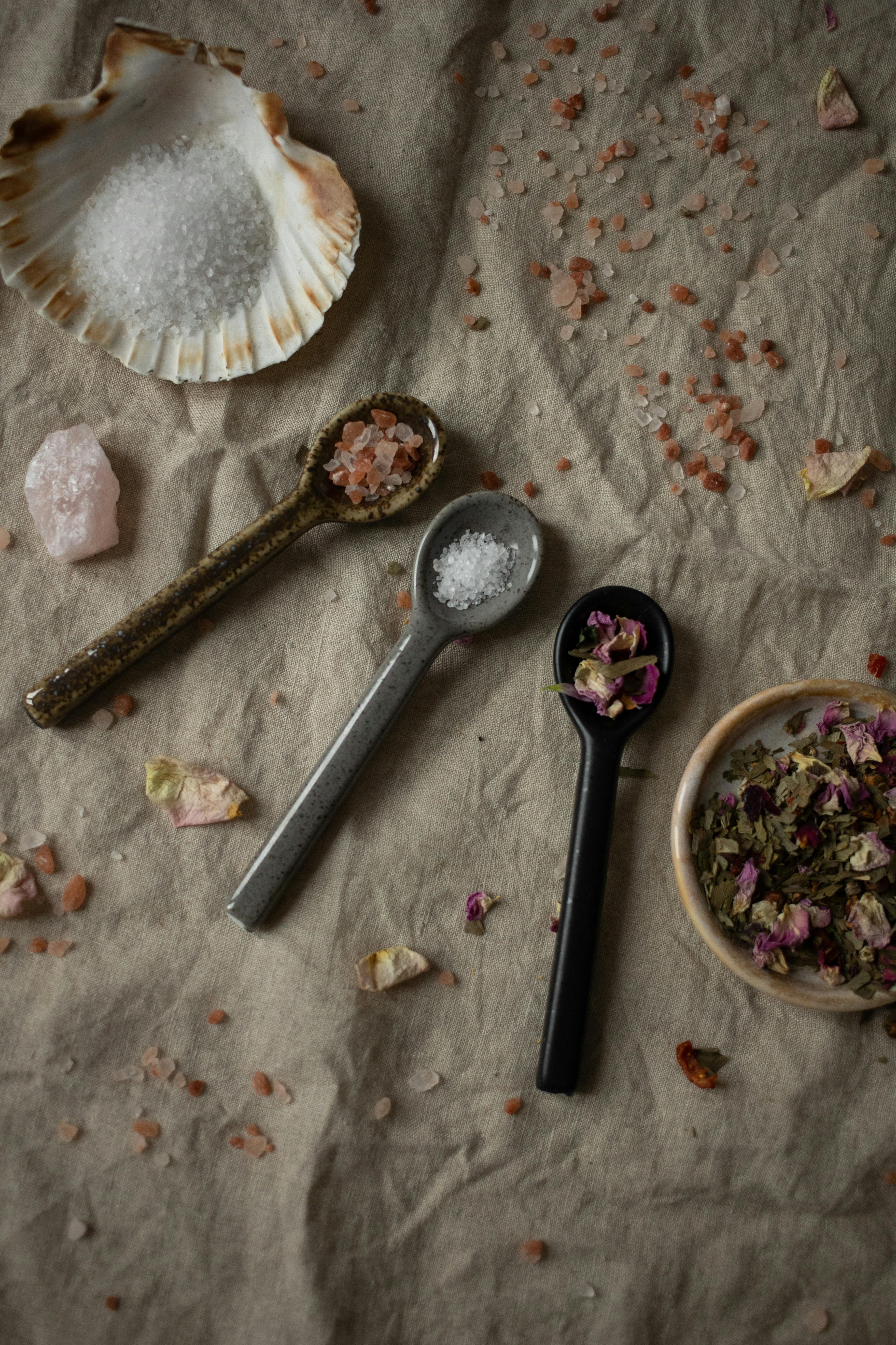 Free Three spoons with salts, spices, and dried petals on a rustic canvas background, offering a textured and artistic composition. Stock Photo