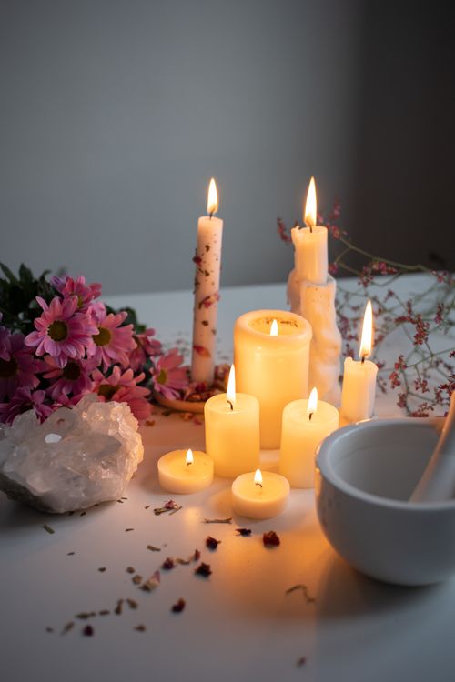 Free Peaceful aromatherapy scene with candles, flowers, and a crystal on a white surface. Stock Photo