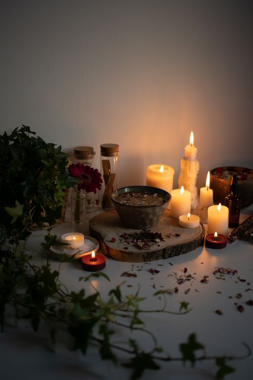 Free Rustic setup featuring burning candles, herbs, and petals on a wooden surface, creating a warm ambiance. Stock Photo