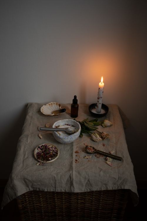 Free Warm, intimate scene of a candlelit table with herbs, flowers, and a mortar and pestle. Stock Photo