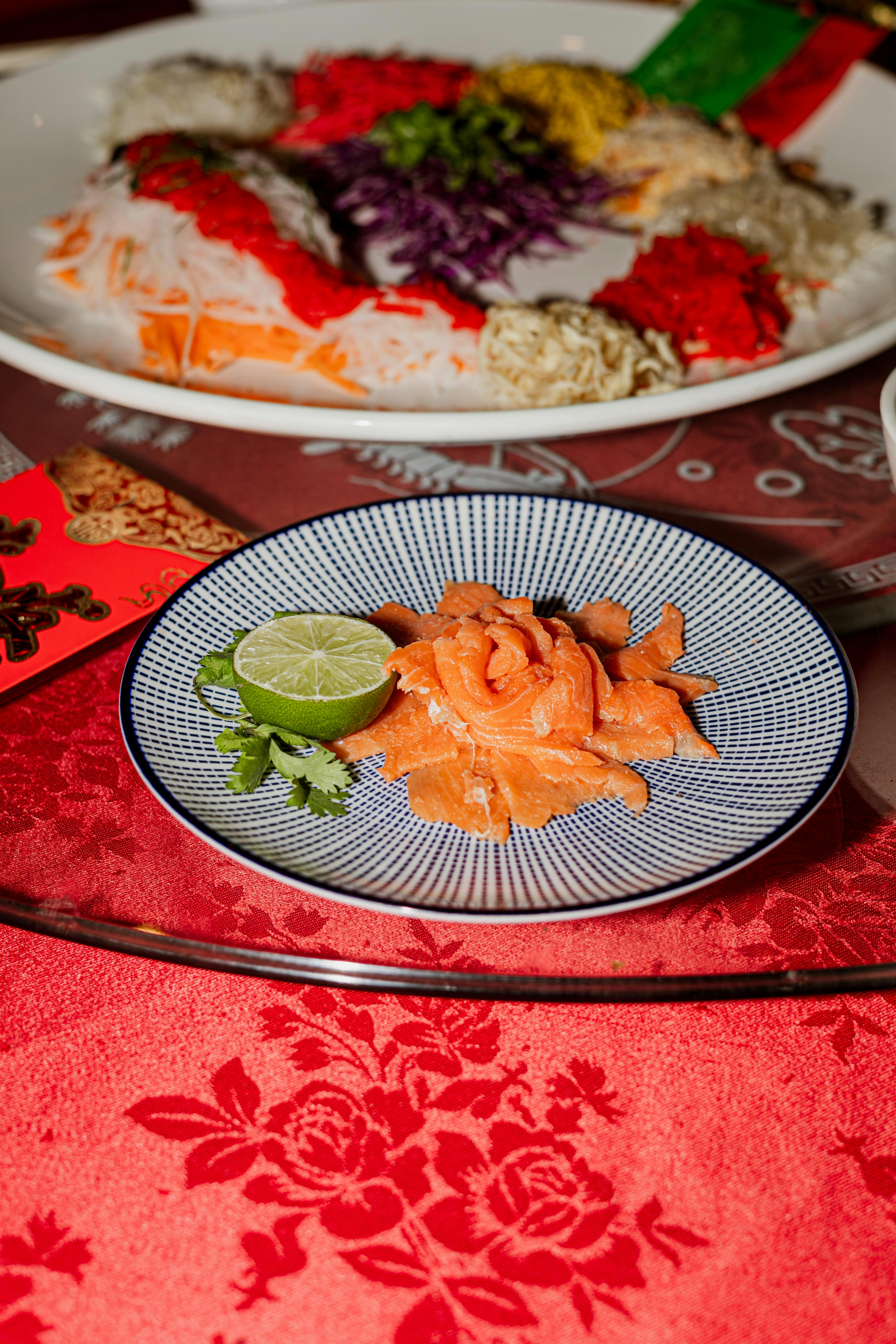 Fresh raw salmon served with lime and herbs on decorative plate, perfect for culinary presentations.