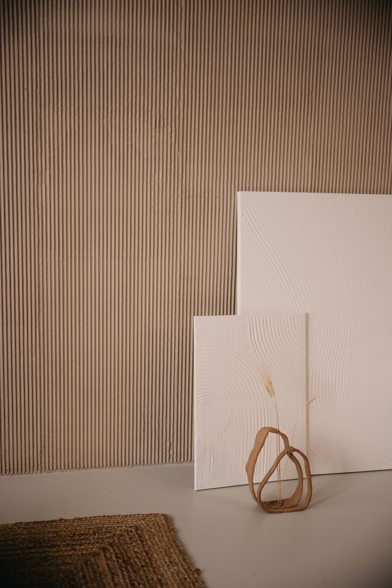 A minimalist composition featuring empty canvases and a vase against a textured wall.