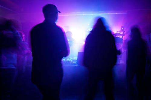 People are silhouetted in a dark room with purple lights