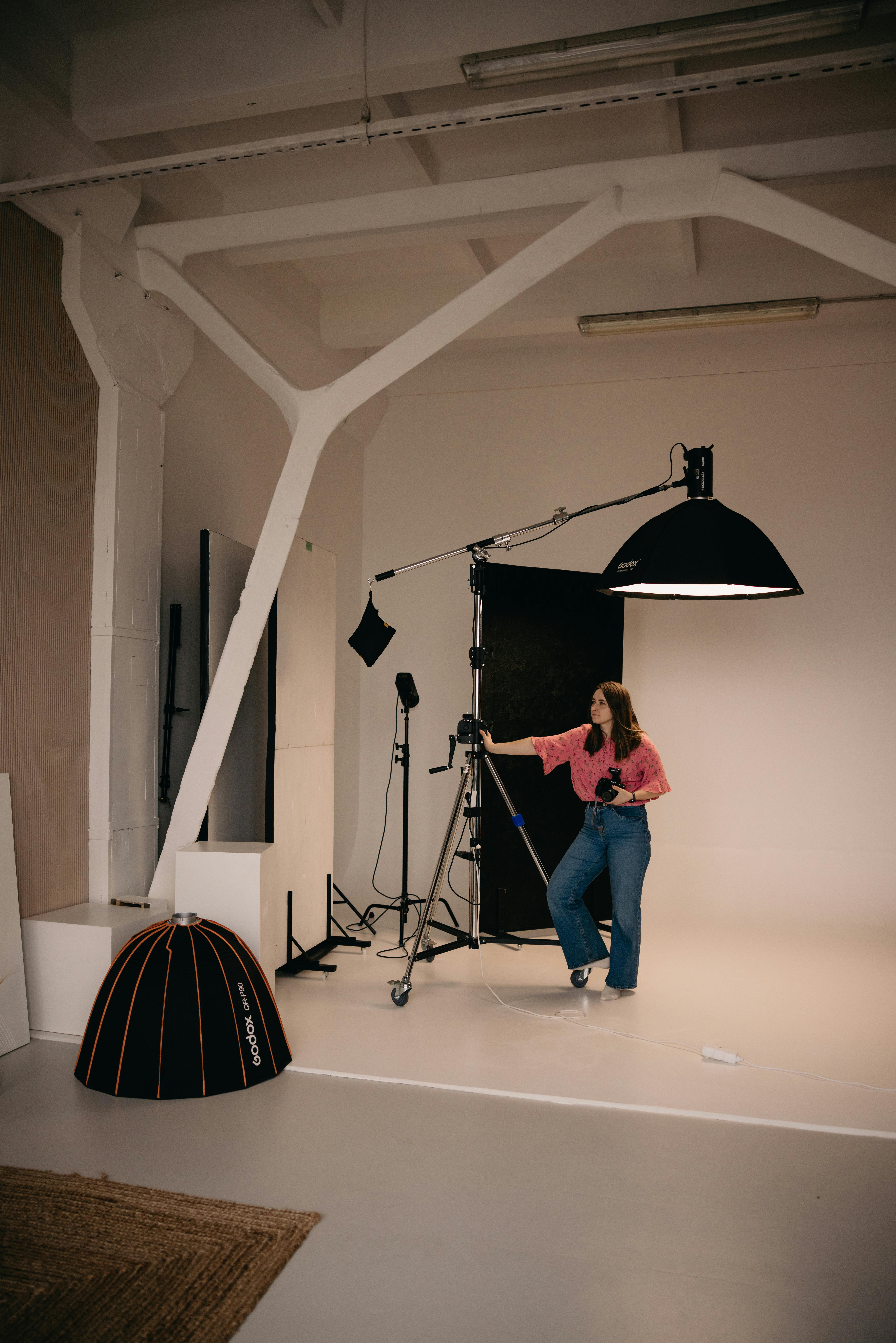 Woman setting up lighting equipment in a professional photography studio.