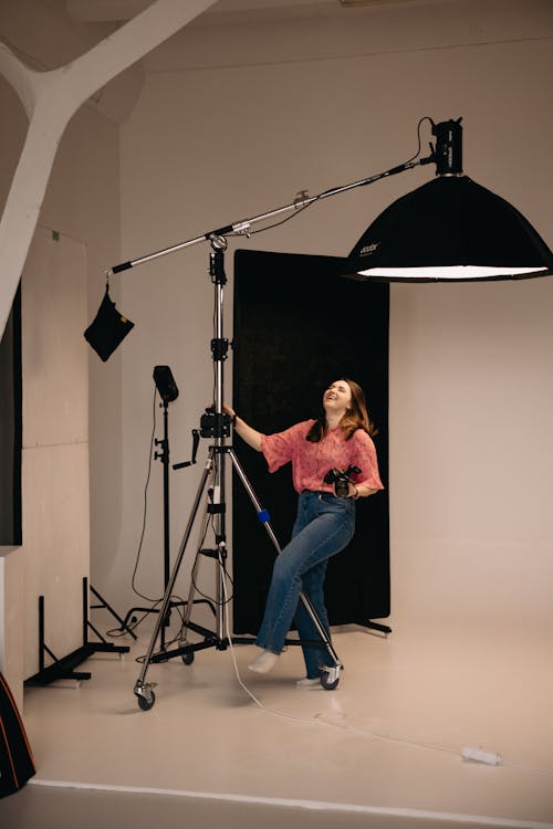 A woman standing in a studio with a camera