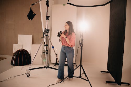 A woman is standing in a studio with a camera