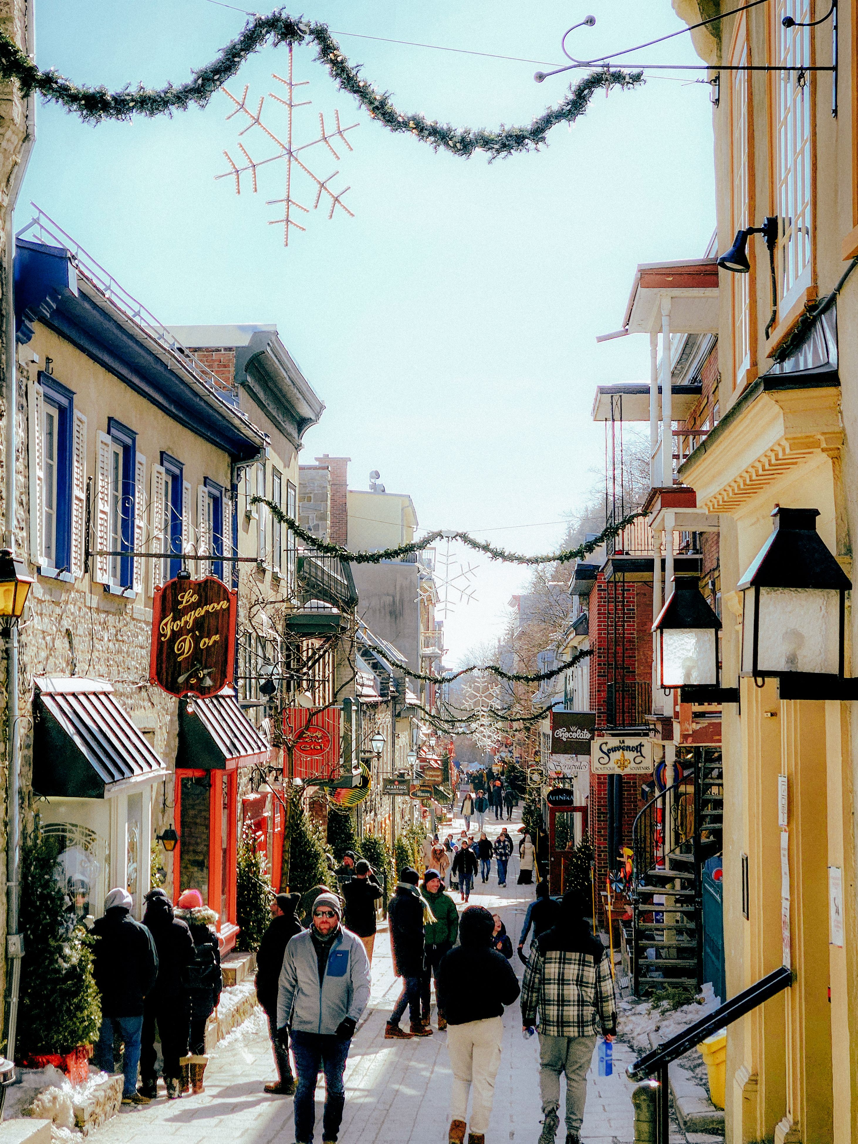 A festive street view in Quebec City with decorations, capturing the winter holiday spirit and local architecture.