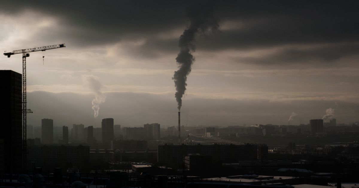 A person checking an air quality app on their phone while standing near a hazy city skyline