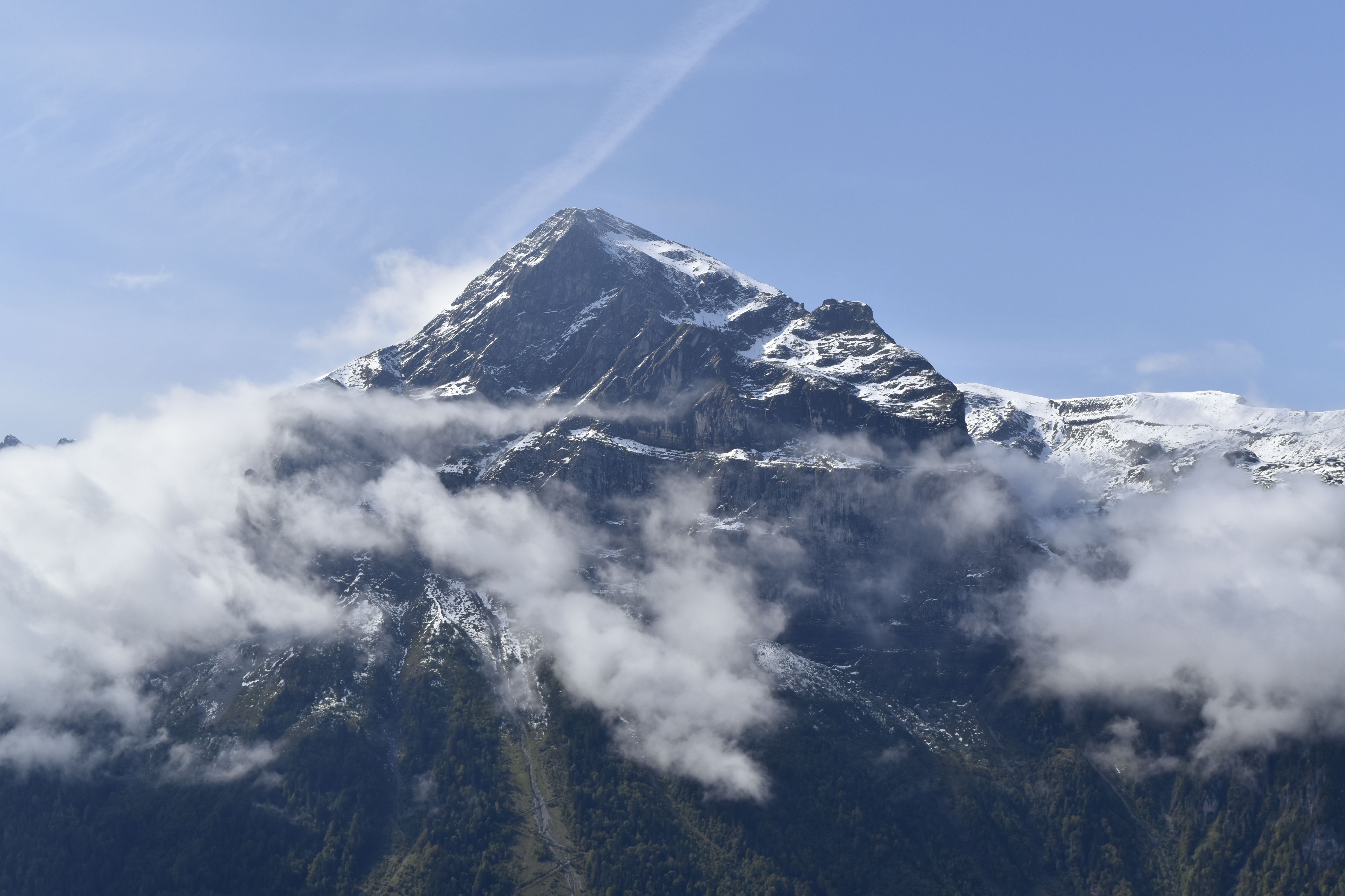 A mountain covered in clouds with a large snow peak · Free Stock Photo