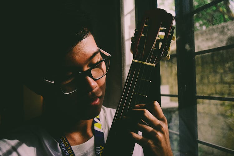 Man Playing String Instrument Near Window Panel