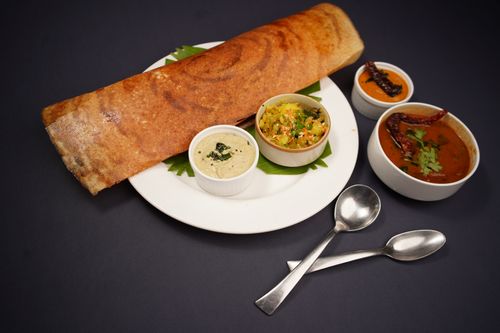 Free Crispy dosa served with coconut chutney, vegetable curry, and sambar on a black background. Stock Photo