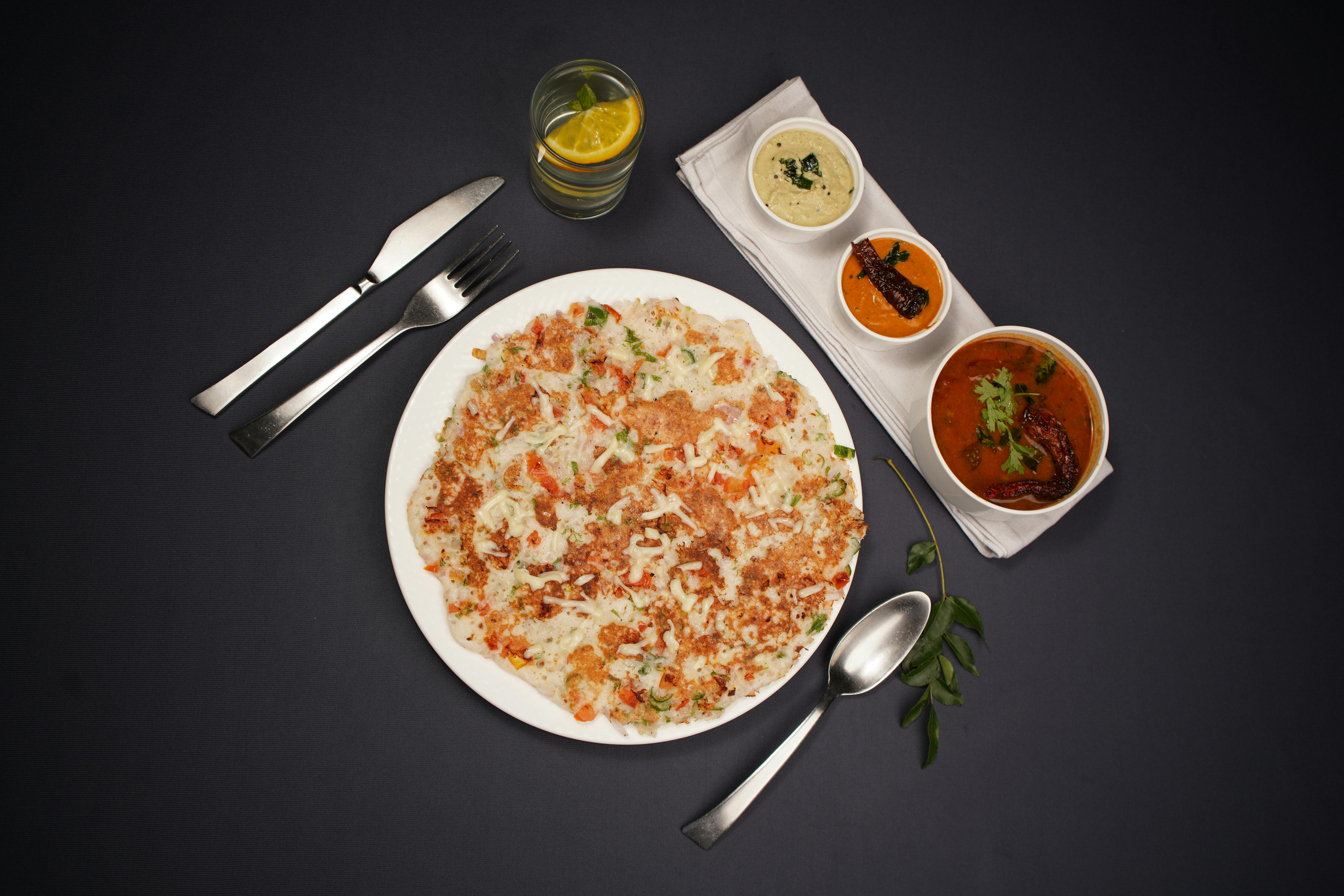 Top view of South Indian dosa served with various chutneys on a black background.