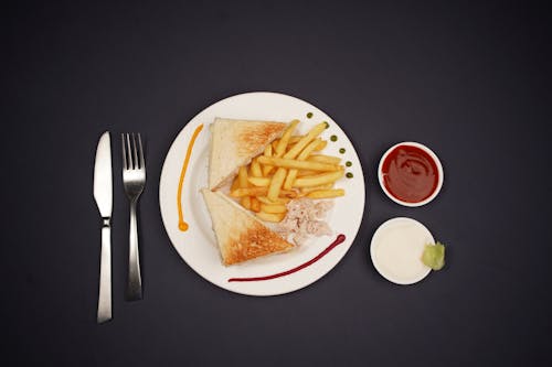 A plate with a sandwich, fries and ketchup
