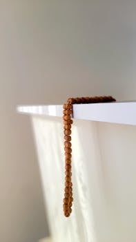 A simple wooden bead necklace elegantly draped over a white surface, showcasing minimalist style.