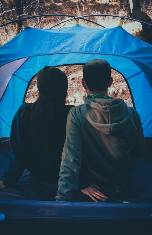Two people sitting in a tent in the woods