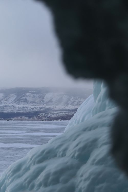 Free Scenic winter view of a frozen lake and snowy hills in misty conditions, perfect for seasonal themes. Stock Photo