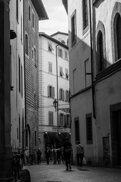 Black and white photo of people walking down a narrow street