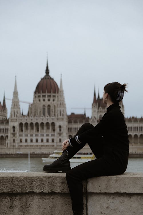 A woman sitting on a ledge looking at the budapest castle