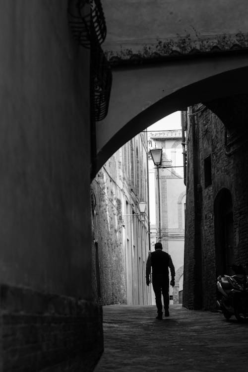 A man walking down an alleyway in black and white