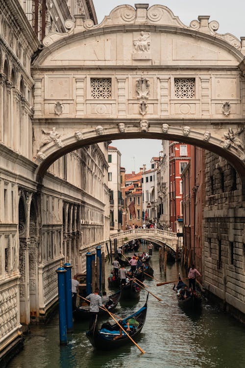 Gondolas are traveling under an archway in venice