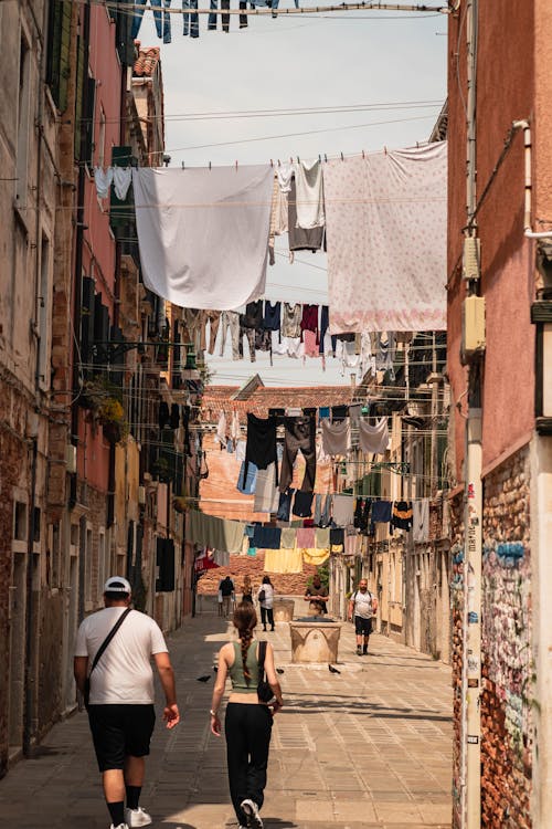 A couple walking down a narrow alleyway with clothes hanging on the line