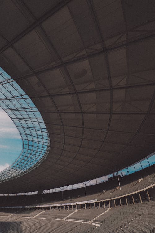A stadium with a large roof and a blue sky