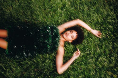 A woman laying on the grass in a green dress
