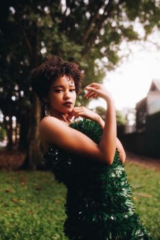 A stylish woman poses confidently in a striking green dress outdoors.